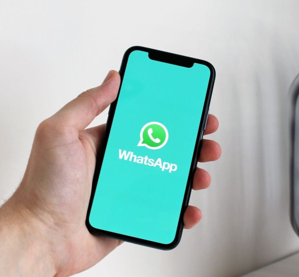 Hand holding a smartphone with the WhatsApp app open for WhatsApp marketing